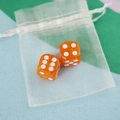 A pair of tangerine orange 5/8 inch marbled acrylic mahjong dice with white pips in a sheer organza pouch.
